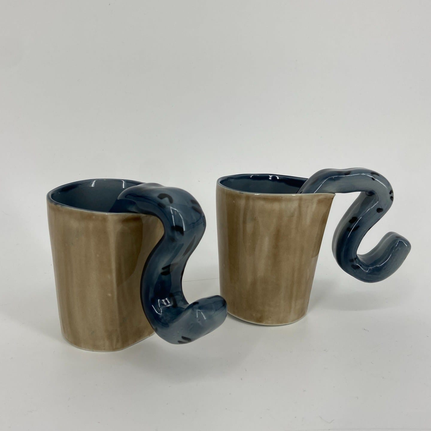 Twee bekers in olijfbruin glazuur met een blauw, slangvormig oor