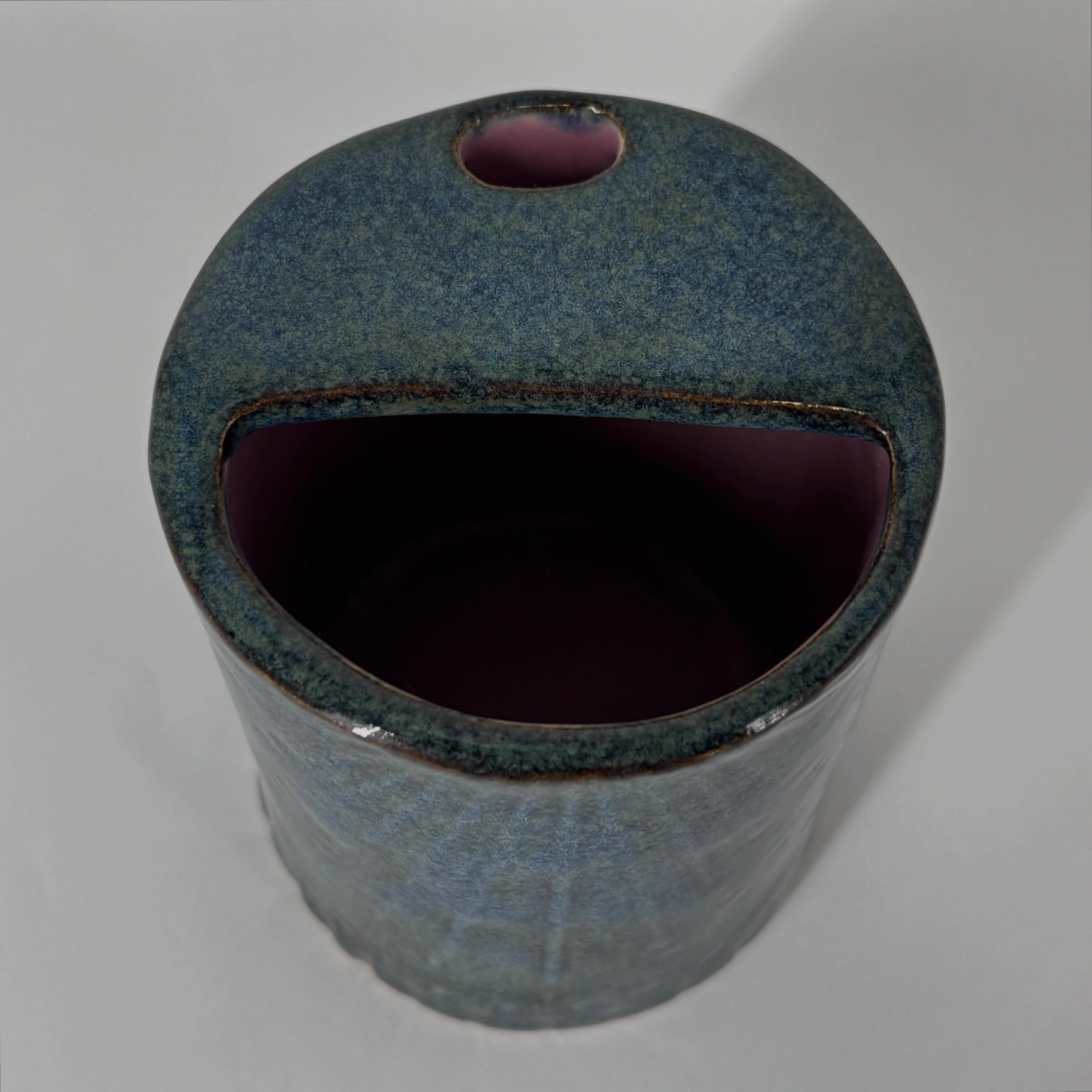 Blauwe cilindervaas met een brede, mondvormige opening en een roze binnenkant