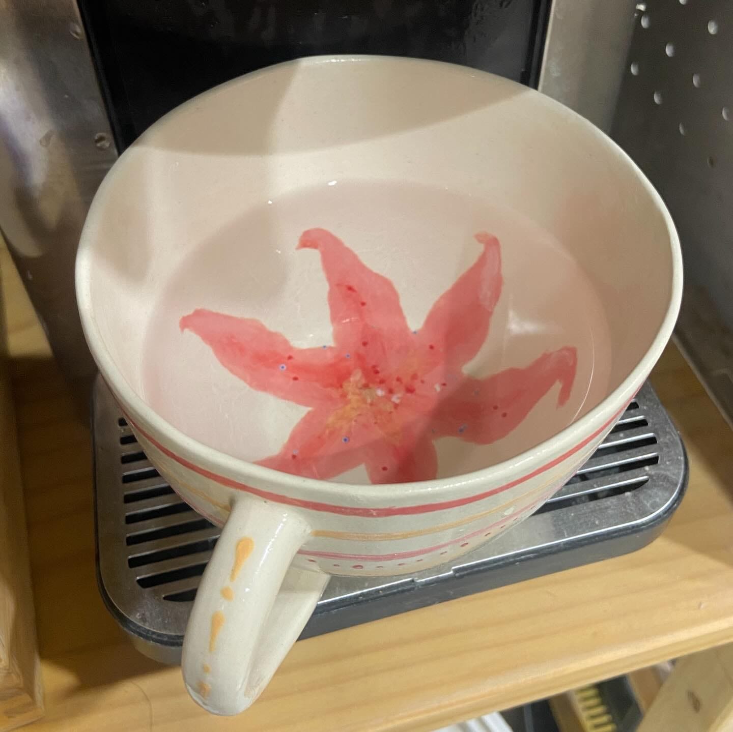 Witte kom met oor en een roze lelie die binnenin is geschilderd, gevuld met water