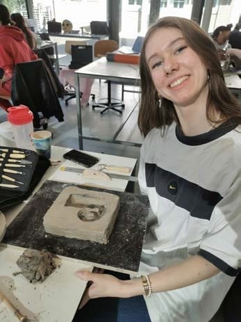 Lachend aan een werktafel met een gipsmal en een geboetseerd model