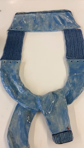 Keramieken trui in blauw glazuur, als een trui over de schouders geknoopt, met gestreepte boorden