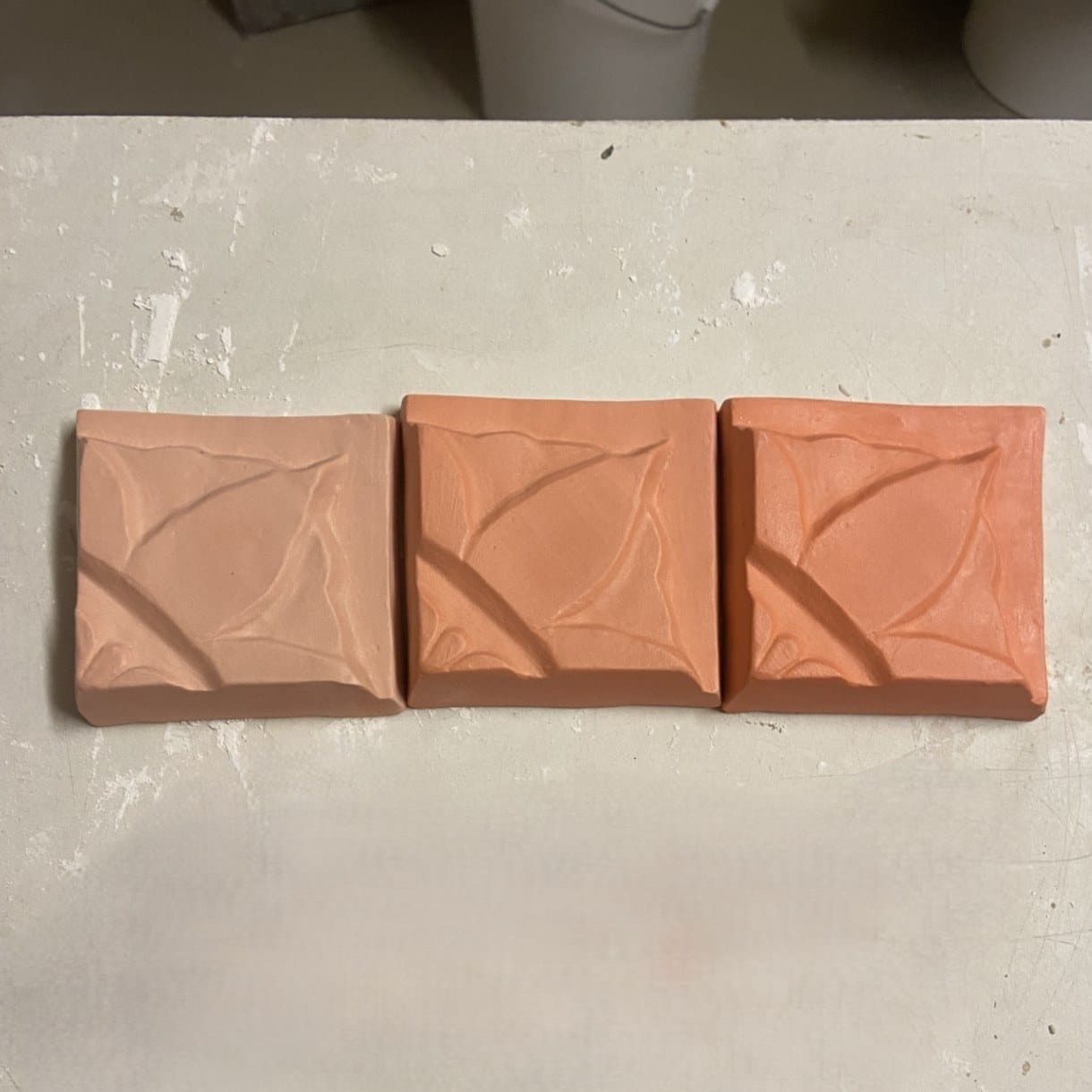 Drie terracotta tegels met een reliëf van bladvormen