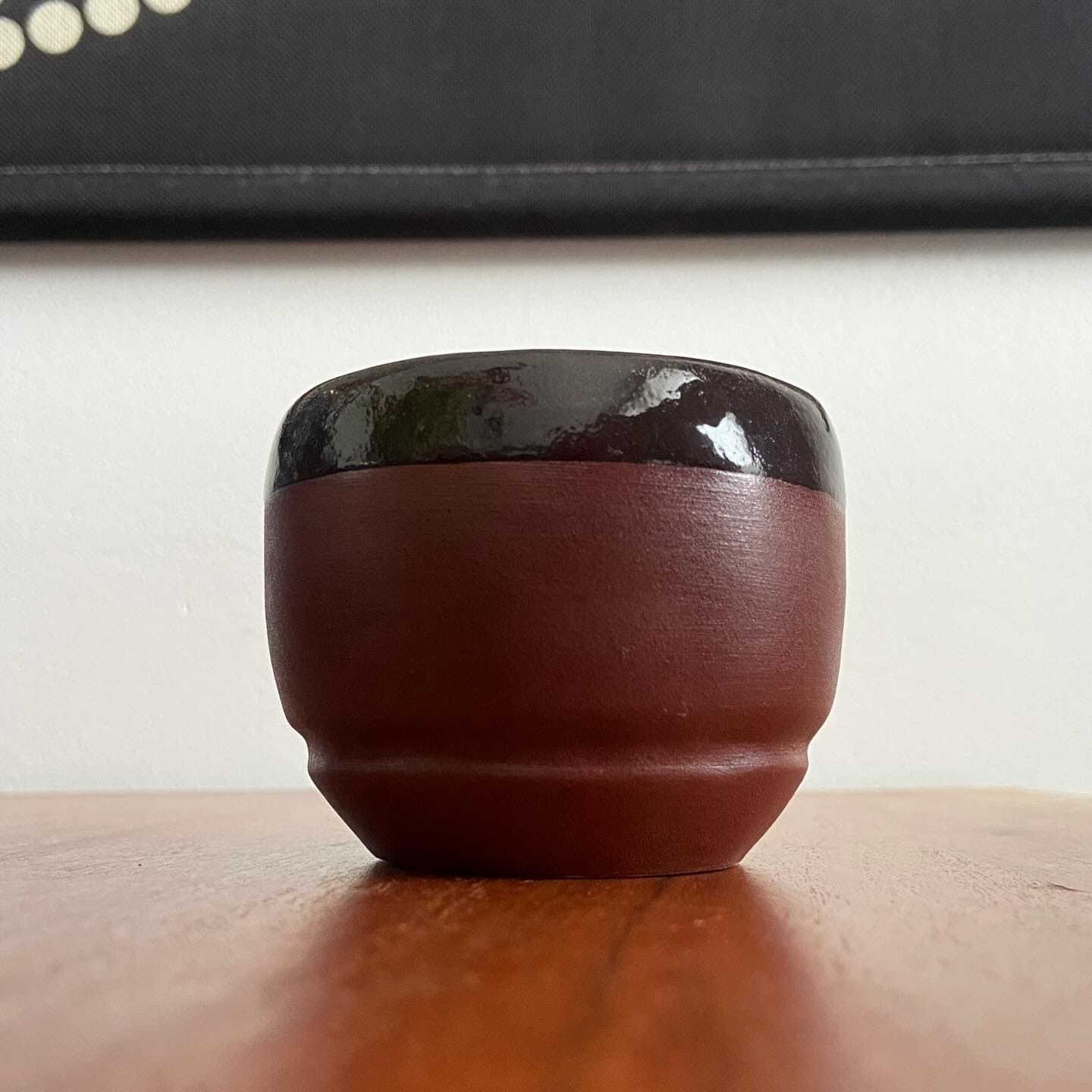 Roodbruine beker met een donker geglazuurde rand op een houten tafel