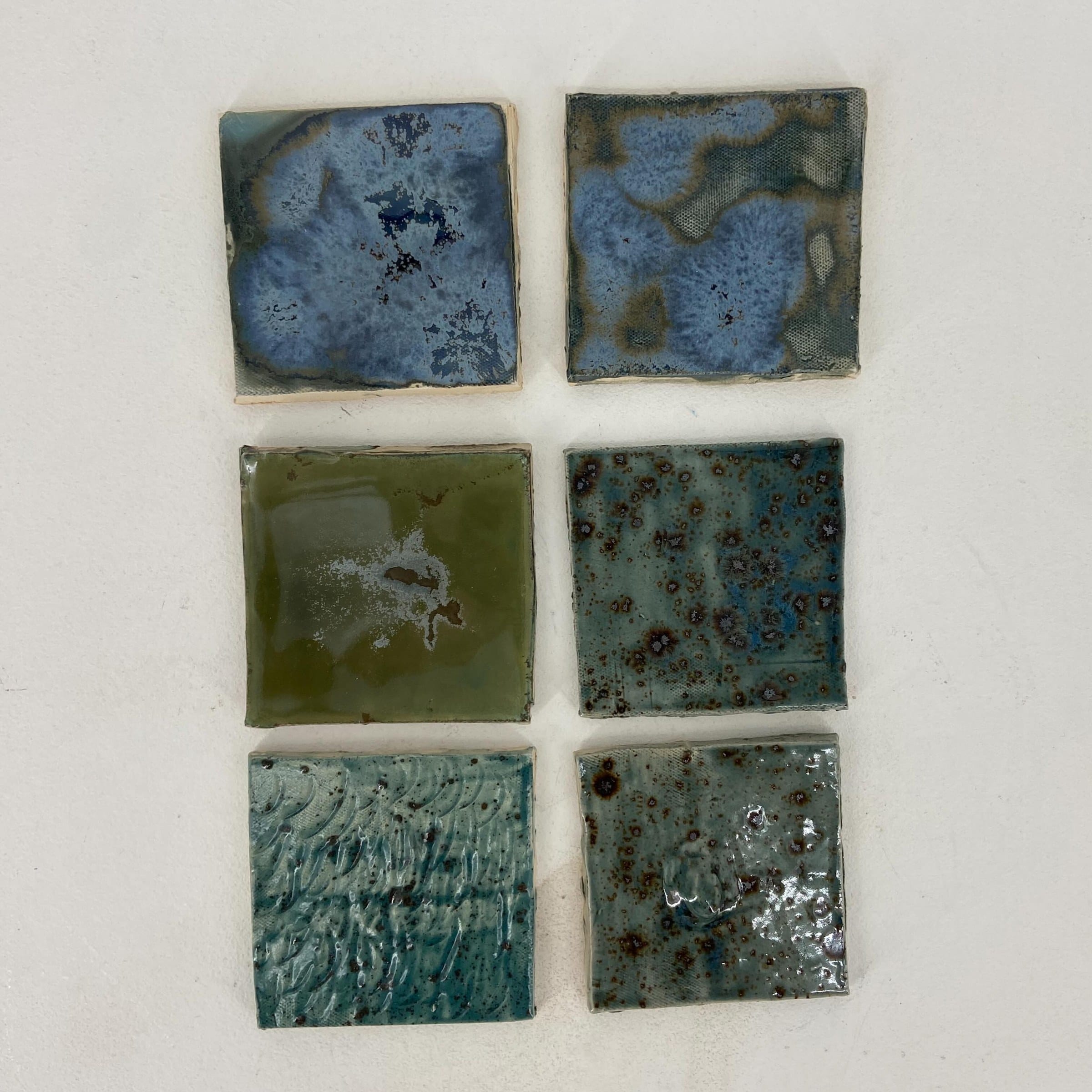 Zes testtegels met blauwe en groene glazuren van dichtbij