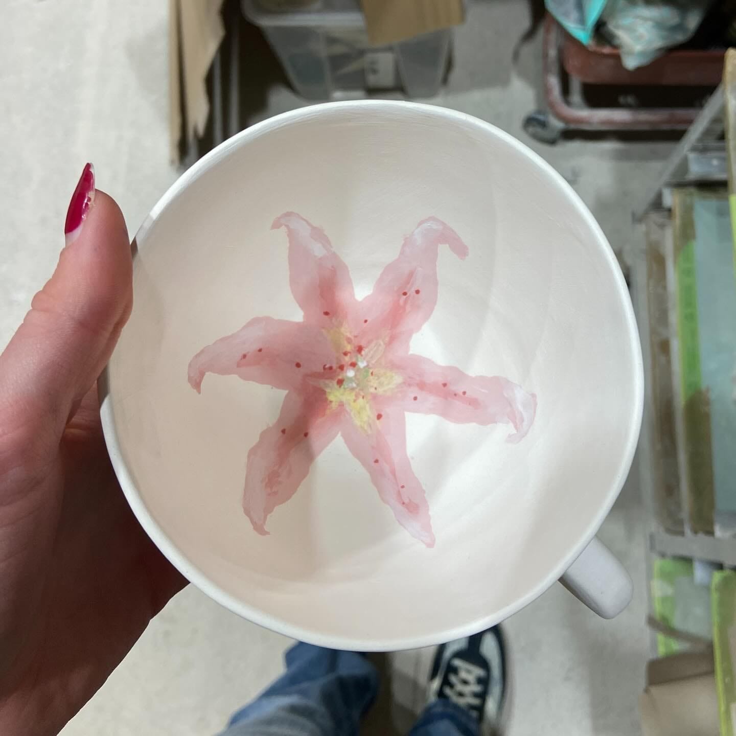 Hand die de kom vasthoudt, met de roze lelie op de bodem