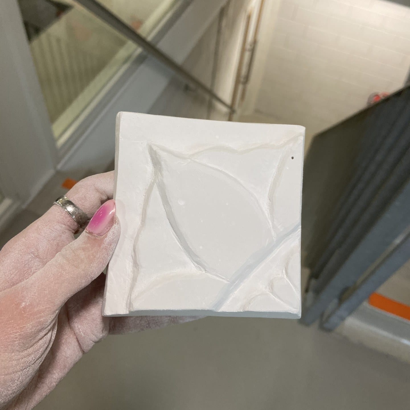 Hand met een witte reliëftegel