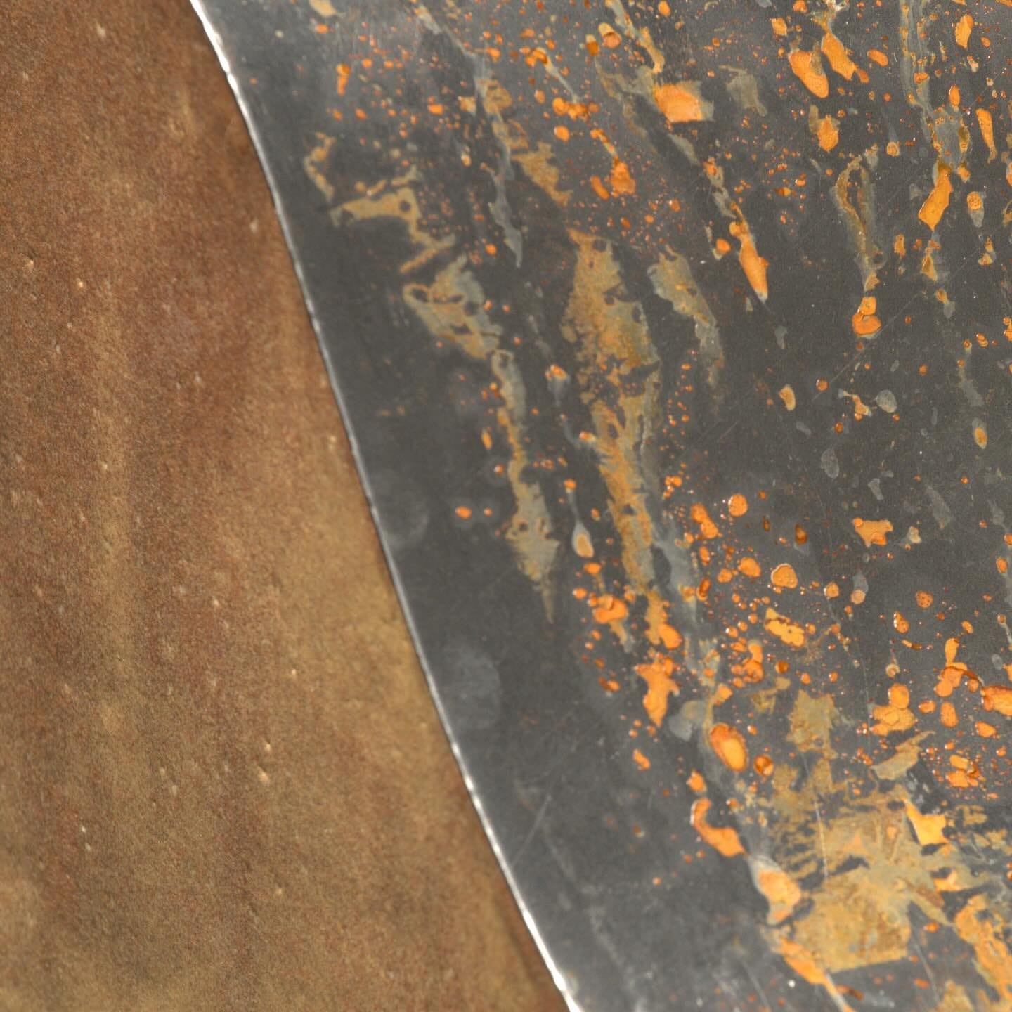 Detail van de gebogen staalplaat met oranje spatten