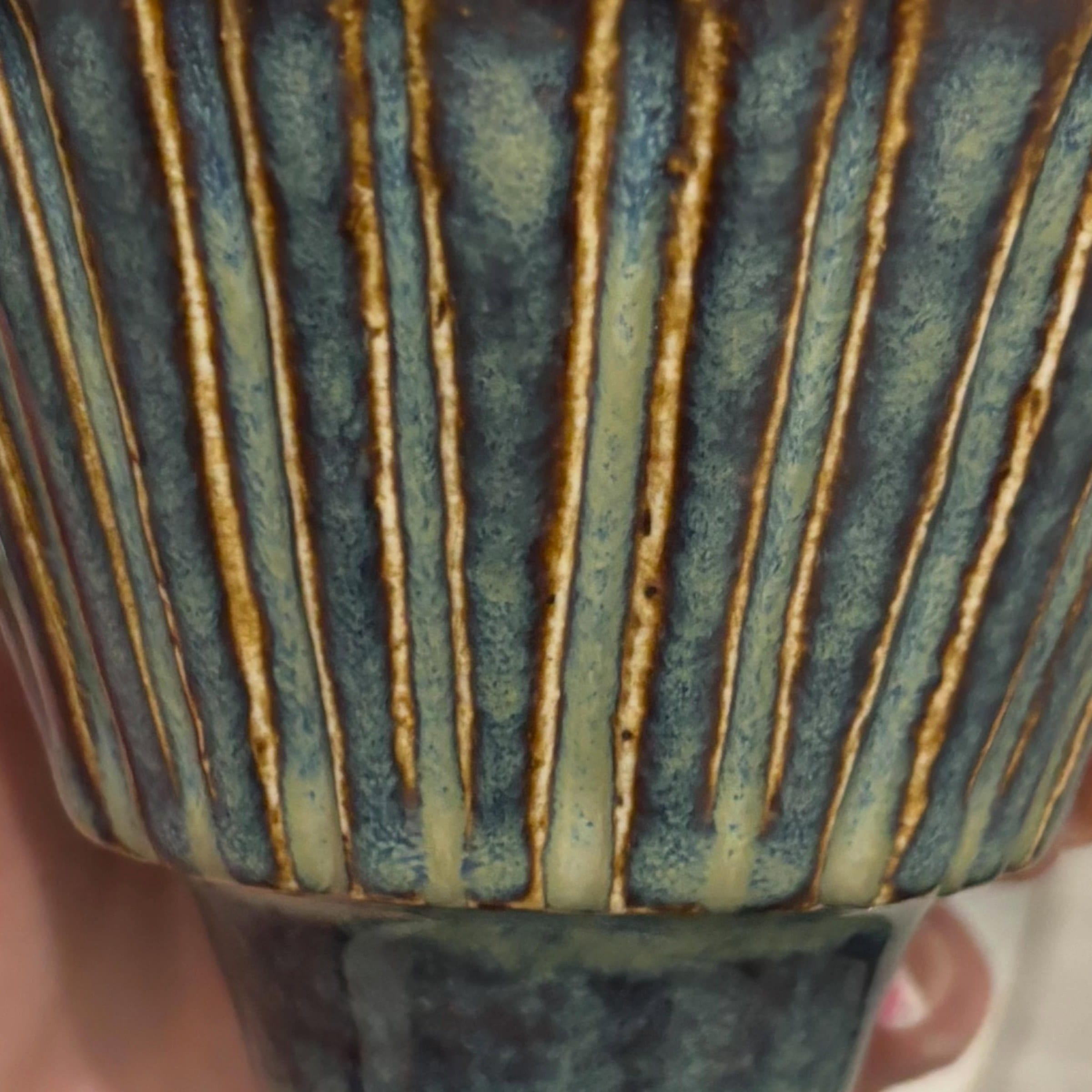 Close-up van de ribbels: blauw glazuur dat op de randen doorbreekt naar bruin