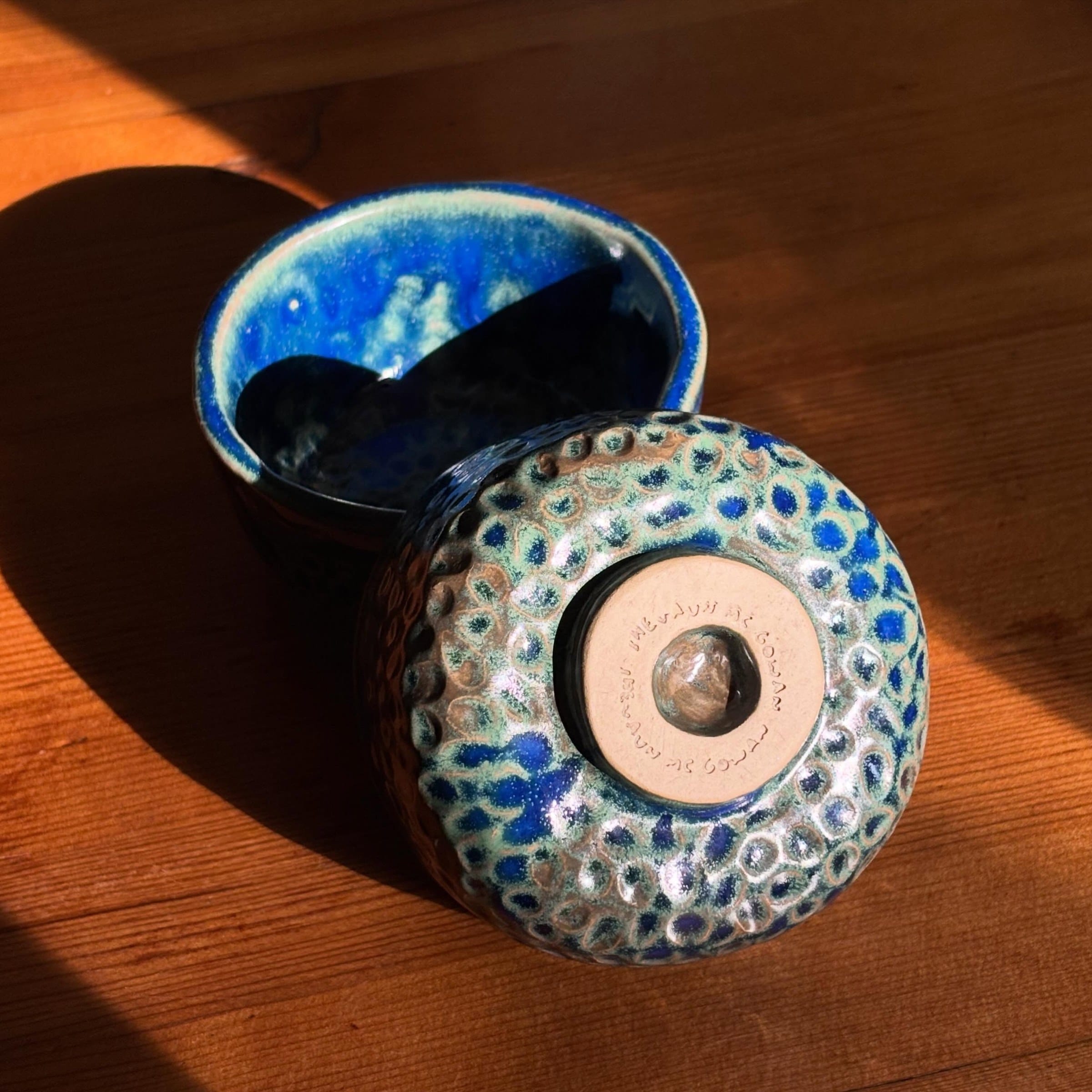 Onderkant van een blauw kommetje met een gestempelde voet, naast een tweede kommetje