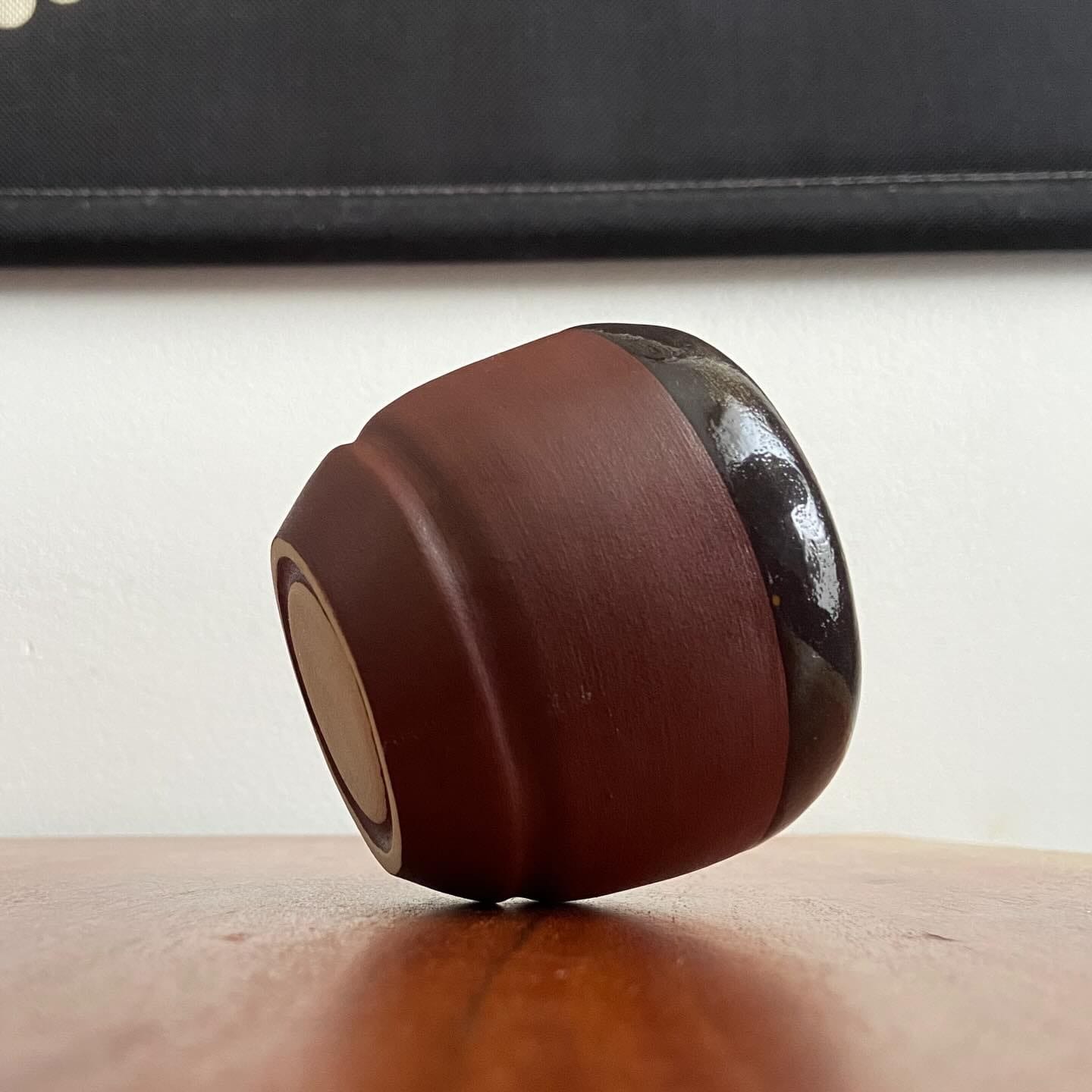Roodbruine beker liggend op een houten tafel