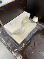 Een witte gipsmal met een gebogen holte op een werktafel