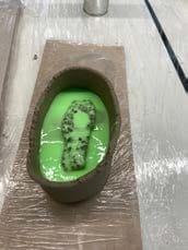 Een model in een bakje van klei, overgoten met groen mallenmateriaal
