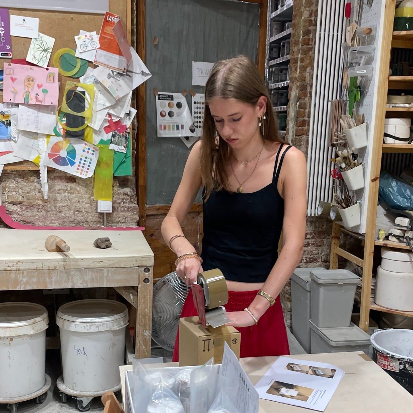 Een doos wordt dichtgeplakt aan de werkbank in het atelier