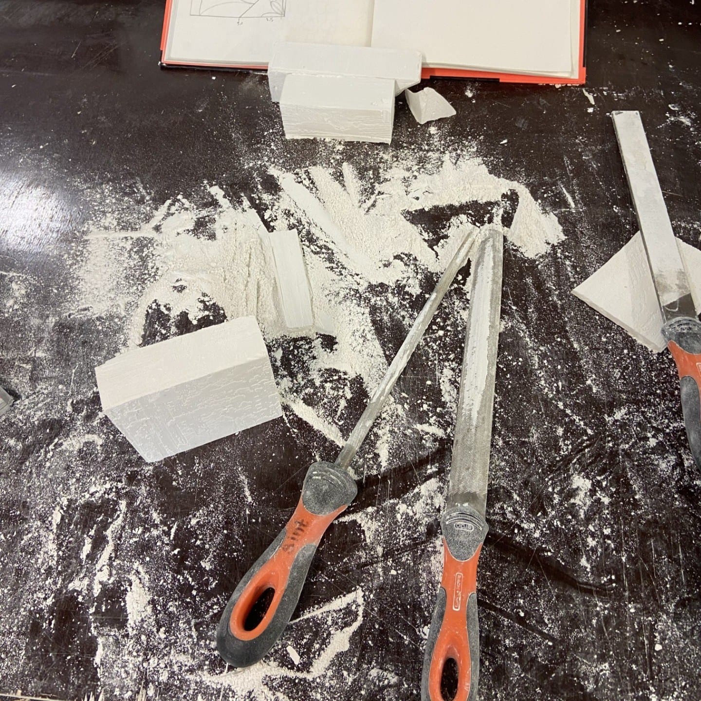 Werktafel vol gipsstof met raspen en blokken gips